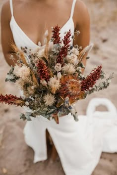 a woman holding a bouquet of dried flowers