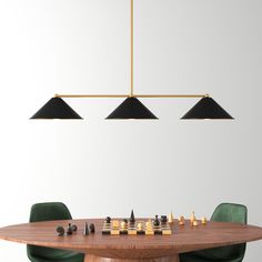 a wooden table topped with chess pieces and green chairs next to a chandelier