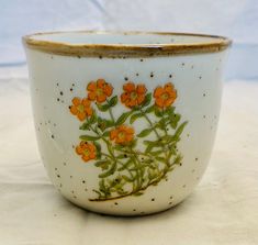 a white bowl with orange flowers painted on the side and gold trim around the rim