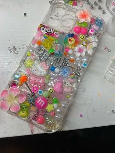 an iphone case covered in lots of different types of candies and buttons on a table