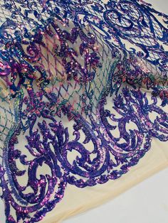 purple and blue sequins on white sheer fabric with intricate design in the center