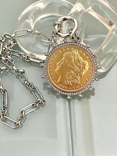 Beautiful reproduction vintage Gold coin pendant, Morgan Peace Dollar coin in a silver bezel with  cubic zirconia stones.  The bale attached to the coin is also encrusted with CZ stones. The coin is 22k gold plated  and elegantly hangs from a multi link Rhodium plated  brass chain and a spring lock CZ clasp The spring lock closure not only makes it easy to open and close the necklace for those with difficulty but adds to the creativity of the jewelry piece.  Will enhance any outfit. Jeans to the little black dress . Perfect for a gift or just for yourself:) Please choose chain length from drop down.  Approximate size of coin and bezel - 50mm  I love it and I know you will too! FAST SHIPPING! Tips to keep your jewelry looking good. 1) Keep jewelry away from water and chemicals. 2) Remove du Gold Coin Pendant, Silver Coin Necklace, Sterling Necklace, Peace Dollar, Book Photo, Dollar Coin, Photo Locket, Gold Coin, Charm Pendant Necklace