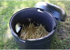 a black trash can filled with straw on top of grass