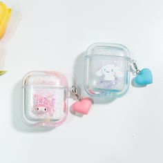 two clear cases with charms on them sitting next to yellow flowers and tulips