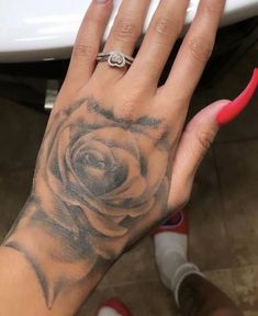 a woman's hand with a rose tattoo on it and a pink ring in the middle