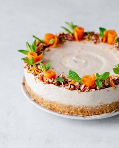 a cake with carrots and nuts on top is sitting on a white platter