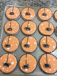 cupcakes decorated with orange frosting and black spider decorations on a baking sheet