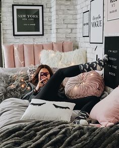 a woman laying on top of a bed covered in pillows