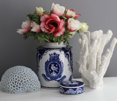 a vase with flowers in it sitting on a table next to some corals and sea urns