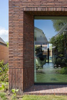 the reflection of a house and lawn in a glass door on a brick building's exterior