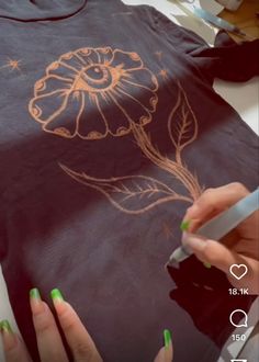 someone is drawing on a t - shirt with green nail polish and an electric pen