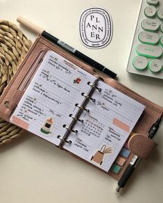 an open planner sitting on top of a table next to a pen and calculator