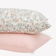 two pillows on top of each other in pink and green floral print, one is made from cotton