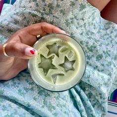 a woman is holding a glass with ice cubes in it