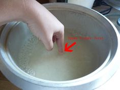 a hand is pointing at the water in a pan on top of a stovetop