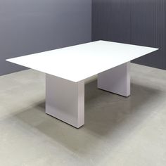 a white table sitting on top of a cement floor next to a gray and grey wall