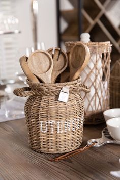 wooden utensils in a wicker basket on top of a table with white dishes