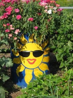 a yellow and blue flower pot with sunglasses on it's face surrounded by pink flowers