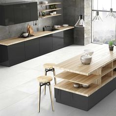 a modern kitchen with black cabinets and wooden counter tops, white tile flooring and an island in the middle