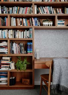 a bookshelf filled with lots of books next to a wooden table and chair