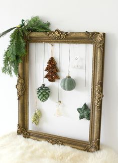 a gold frame with ornaments hanging from it's sides in front of a white wall