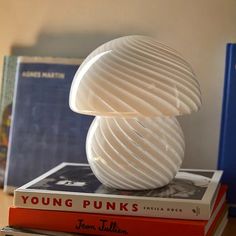 two books are stacked on top of each other next to a white lamp that is shaped like a mushroom