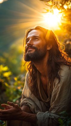 a man with long hair and beard sitting in the grass looking up at the sun