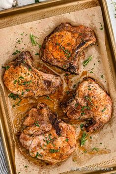 four pieces of chicken on a baking sheet covered in gravy and garnished with fresh herbs