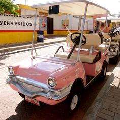 an old pink golf cart is parked on the street