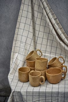 a stack of coffee cups sitting on top of a white tablecloth covered chair next to a window