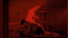 a man sitting on top of a bed under a red light