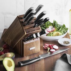 an assortment of kitchen knives and vegetables on a table