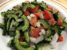 a white plate topped with broccoli and tomato salad on top of a wooden table