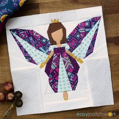 the paper doll is made to look like an angel with purple wings and blue dress