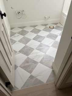 a bathroom with white and gray tile flooring next to a doorway that leads to a toilet