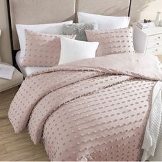 a bed with pink comforter and pillows on it