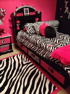 a zebra print bedroom with pink walls and black bedding, rugs and drawers