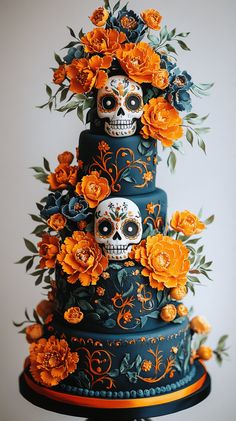 a three tiered cake decorated with sugar skulls and orange flowers on a black stand