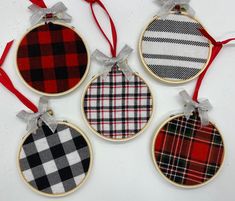 four christmas ornaments hanging from red ribbon on white tablecloth with checkered plaid pattern