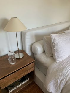 a bed with white sheets and pillows next to a night stand