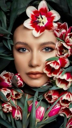 a woman with flowers in her hair is surrounded by green leaves and pink tulips