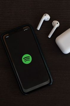 an iphone and ear buds sitting on top of a wooden table next to each other