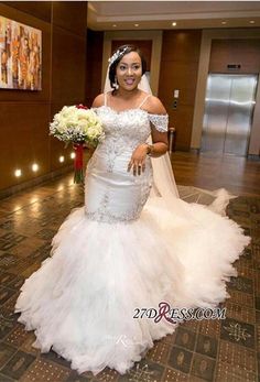 a woman in a white wedding dress standing on a tiled floor with flowers and a bouquet