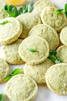 some cookies are on a white plate with mint sprigs and lemon wedges