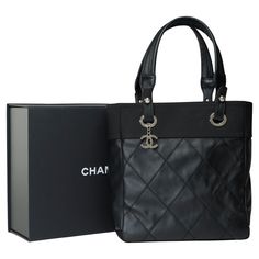 Elegant​ ​Chanel​ ​Paris-Biarritz​ ​Tote​ ​bag​ ​in​ ​black​ ​coated​ ​canvas​ ​and​ ​black​ ​canvas,​ ​silver​ ​metal​ ​trim,​ ​double​ ​black​ ​canvas​ ​handle​ ​for​ ​a​ ​hand​ ​or​ ​shoulder​ ​carry A​ ​zipper Inner​ ​lining​ ​in​ ​black​ ​canvas,​ ​one​ ​zipped​ ​pocket Signature:​ ​"Chanel®​ ​Made​ ​in​ ​Italy" Date:​ ​2011 Dimensions:​ ​27x26x11​ ​cm​ ​(10,7x10,3x4,3​ ​Inches) Reference:​ ​101698 Packaging Hologram:​ ​Yes Card​ ​of​ ​authenticity:​ ​No Dustbag:​ ​No Box:​ ​Yes General​ ​c Chanel Large Tote Bag, Chanel Shopping Bag Tote, All Black Chanel Bag, Chanel Limited Edition Bag, Chanel Tote Bag Black, Chanel Paris, Metal Trim, Carry On Bag, Black Canvas