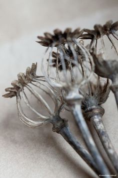 three metal flowers are sitting on a table top, one is wilted and the other is dying