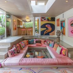 a living room filled with lots of furniture and paintings on the wall next to stairs