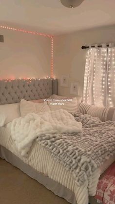 a large bed sitting in a bedroom next to a window with lights on the wall