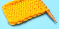 a yellow knitted piece with a wooden needle sticking out of it's end