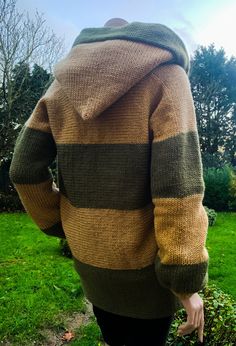 the back of a woman's sweater in brown, green and black stripes on grass